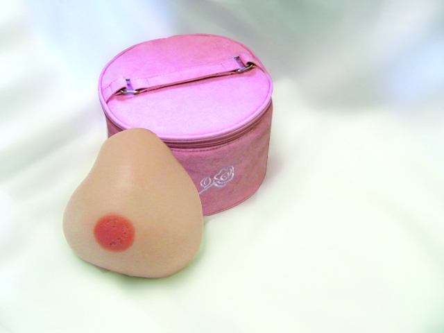 a breast prosthesis sits upright leaning against a pink carrying case